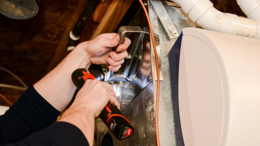 HVAC technician drilling a unit